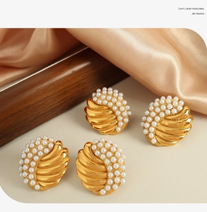 Detailed shot of gold-tone vintage shell earrings with inlaid pearls on silk background
