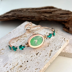 Elegant rose gold oval bracelet watch with green gemstone inlay on porous stone