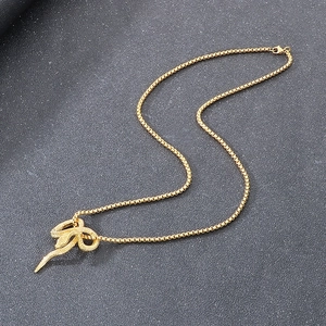 Close-up of golden zodiac snake pendant with polished box chain on grey background
