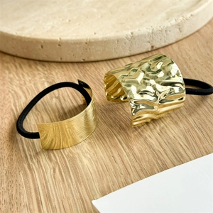 Detailed view of irregular gold metal hair rings with brushed and hammered textures
