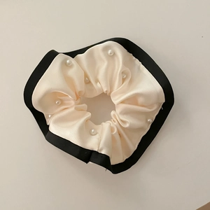 Detalle de coletero crema con borde negro y adornos de perlas elegantes incrustadas
