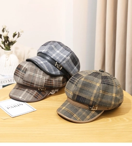 Detailed macro view of plaid newsboy caps with leather straps and gold metal buttons