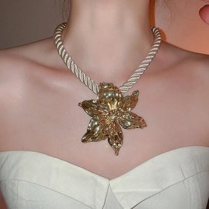 Close-up of golden flower pendant necklace with beige twisted rope chain on model
