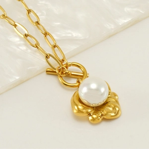 Macro shot of 18K gold chain necklace with large white pearl pendant and toggle clasp