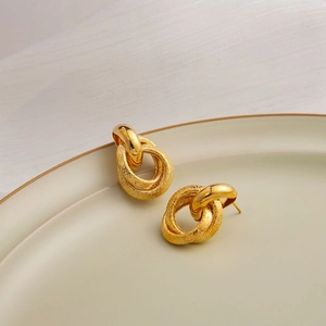 Detail of interlocking gold triple hoop earrings with smooth and frosted textured finishes