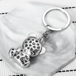 Silver bear keychain with heart cutout details on marble stone coaster for backpack