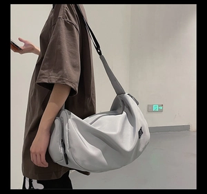 Detailed side view of a large grey waterproof nylon crossbody bag worn by a model