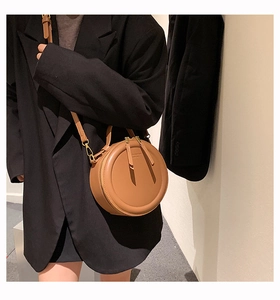 Braune runde Umhängetasche aus Leder, gestylt mit einem schwarzen Blazer