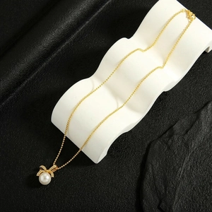 Elegant gold bow necklace with freshwater pearl and zircon pendant on wave prop