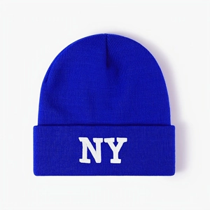Detailed close-up of white NY embroidery on a royal blue ribbed knit beanie hat