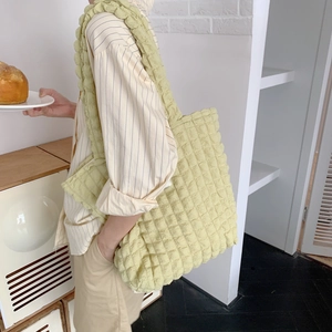 Dettaglio della borsa tote gialla con texture a nuvola, capienza e tracolla in mostra