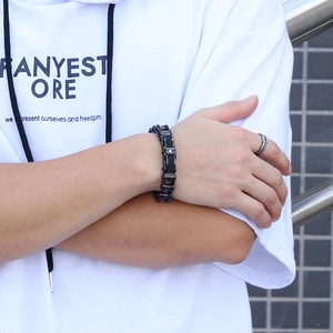 Dettaglio di un bracciale a catena industriale nera e anello intrecciato in argento da uomo