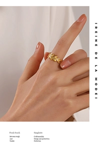 Detail of a golden leaf-shaped stainless steel ring worn on a model's finger