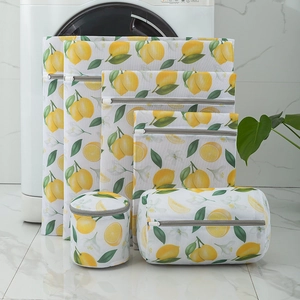 Detailed set of 6 lemon print mesh laundry bags stacked in a modern laundry room decor