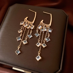 Detail of gold fringe earrings with square zircons on a luxury jewelry box