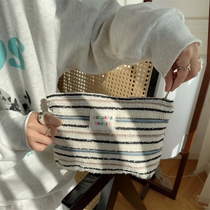 Detailed macro view of the striped canvas pouch featuring a high-quality metal zipper closure