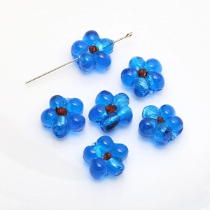 Detailed view of six blue glass flower beads with red centers for DIY jewelry making