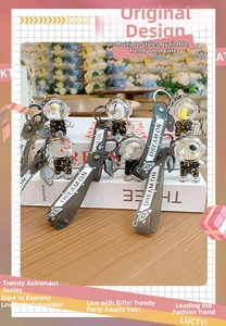 Detail of astronaut liquid quicksand keychains with Dream On strap and gold starry texture