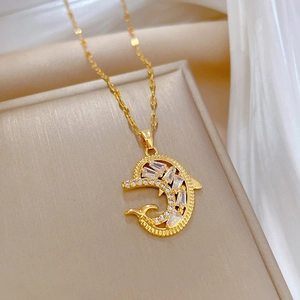 Golden dolphin necklace with zircon crystals on a beige display base for elegant women