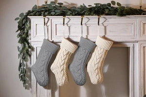 Detail of grey and beige knitted Christmas stockings hanging on a white fireplace