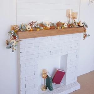 Fall garland with white pumpkins, maple leaves, and LED lights on a white fireplace mantel