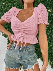 Gros plan sur la texture rose broderie anglaise et le cordon de serrage du haut col en V