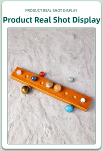 Detail of natural stone solar system planet set on engraved wooden base over grey sand