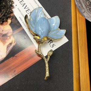 Elegant blue enamel magnolia flower brooch with gold plating on vintage background