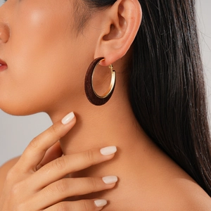 Close-up of woman wearing brown velvet earrings with golden geometric circular frames