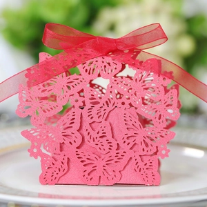 Macro shot of pink laser-cut butterfly candy box with red silk ribbon on a plate