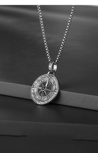 Macro shot of silver-tone compass pendant with engraved directional letters and box chain