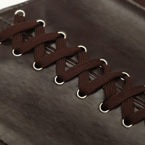 Macro shot of dark brown leather texture with woven laces and silver metal eyelets