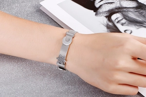 Dettaglio del bracciale a maglia in acciaio argento con ciondoli a fiocco di neve e luna