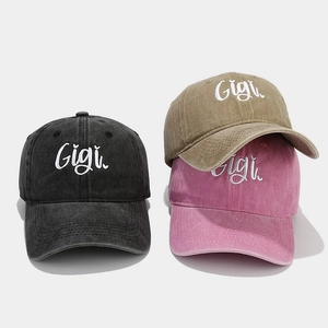 Close-up of Gigi cursive embroidery on washed cotton baseball caps in three colors