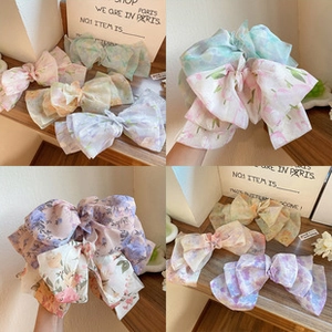 Detail of floral organza bow hair clips in pastel pink, purple, and mint green colors