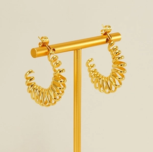 Detailed macro view of 18k gold plated spiral hoop earrings with a spring texture finish