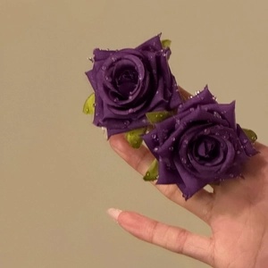 Detailed view of purple fabric rose earrings with delicate water droplet accents