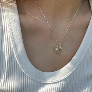 Detail of 925 sterling silver palm tree pendant necklace worn on neck with polished finish