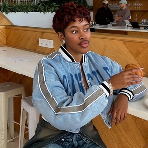Detail of light blue bomber jacket with gray stripes and ribbed collar in cafe setting