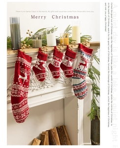 Detail of red and white knitted Christmas stockings with reindeer patterns on a fireplace