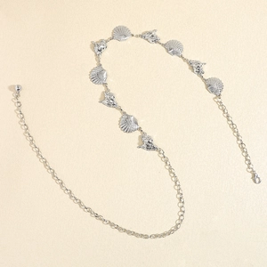 Macro detail of silver starfish and seashell links on a vintage beach body chain belt