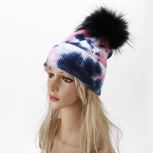 Detailed macro view of the colorful tie-dye knit texture and soft black faux fur pom-pom