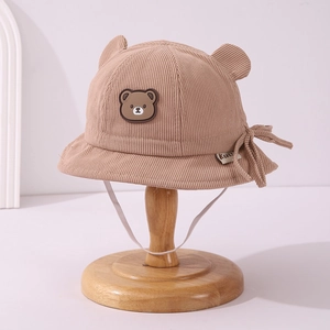 Close-up of light brown corduroy baby hat with cute bear patch and 3D ears detail