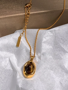 Macro shot of gold plated oval tiger eye pendant necklace with polished finish