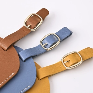 Close-up of PU leather luggage tags with gold buckles in brown, blue, and yellow colors