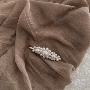 Macro detail of handmade Baroque pearl hair clip with vintage gold alloy base and pearls