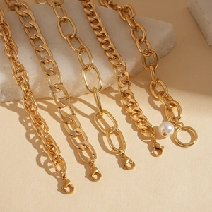 Detailed view of five gold chain bracelets with pearls on a natural white stone base