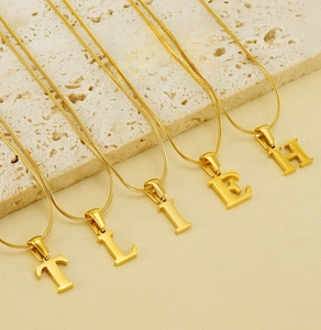 Close-up of golden alphabet T, L, I, E, H pendants on elegant snake bone chains