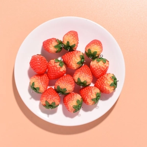 Detailed view of twelve red resin strawberry charms with green leaves and metal rings