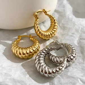 Macro shot of gold and silver croissant hoop earrings with classic spiral texture